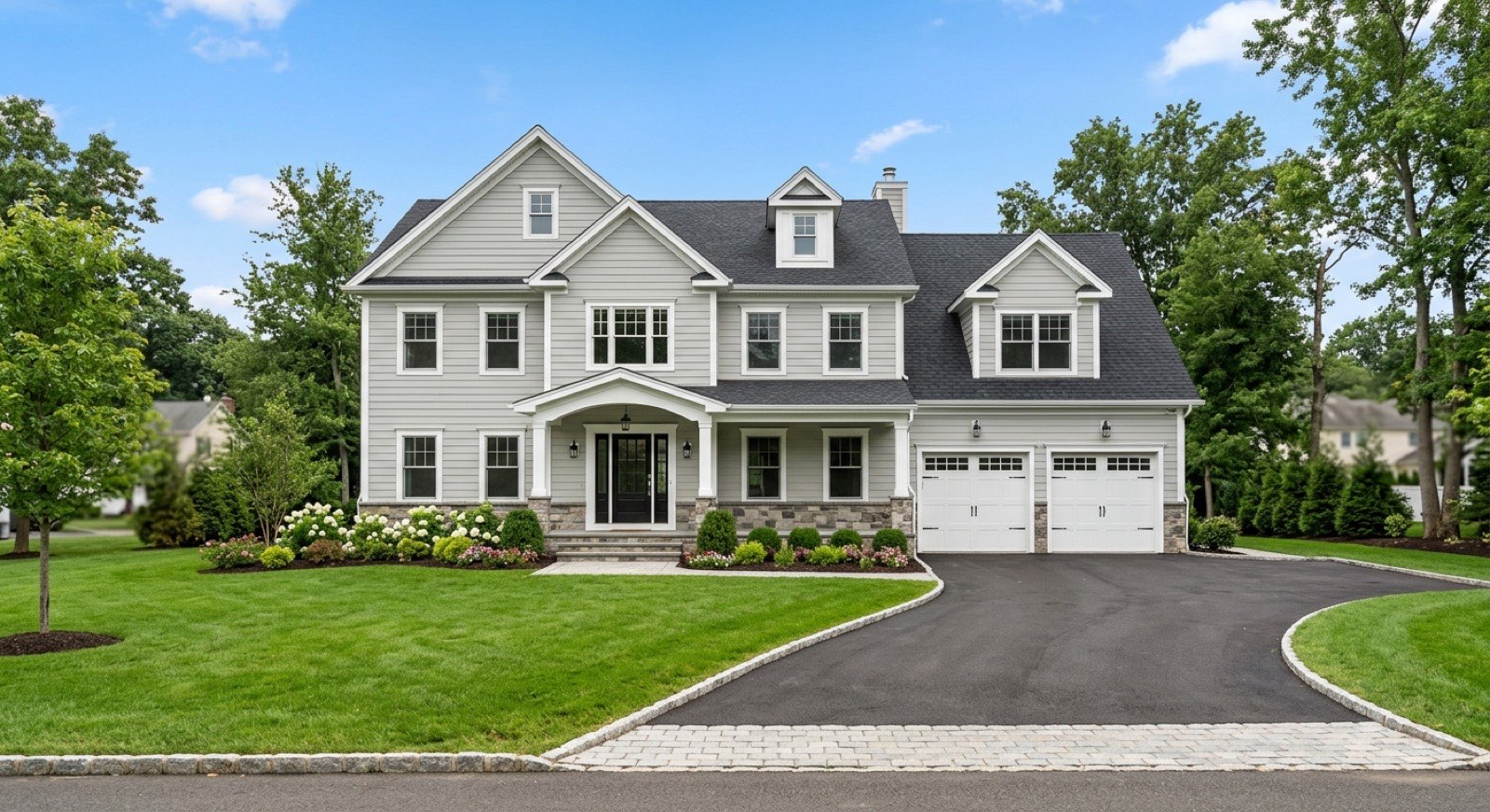 Large modern gray colonial with a two-car garage and landscaped lawn in South Brunswick, NJ